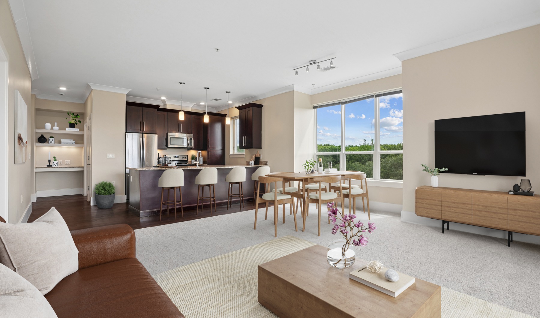 Wide banner view of the open-concept kitchen and living area inside a luxury Matrix Hudson apartment, featuring high-end finishes and a bright, welcoming layout in Hudson, MA.