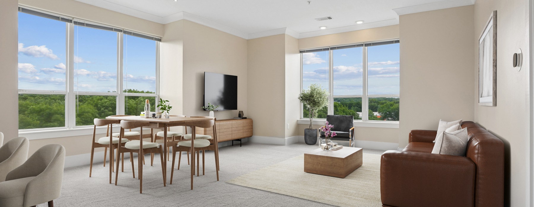 Wide banner view of a spacious and bright apartment living room at Matrix Hudson, showcasing an open layout that connects to a dining and kitchen area in Hudson, MA.